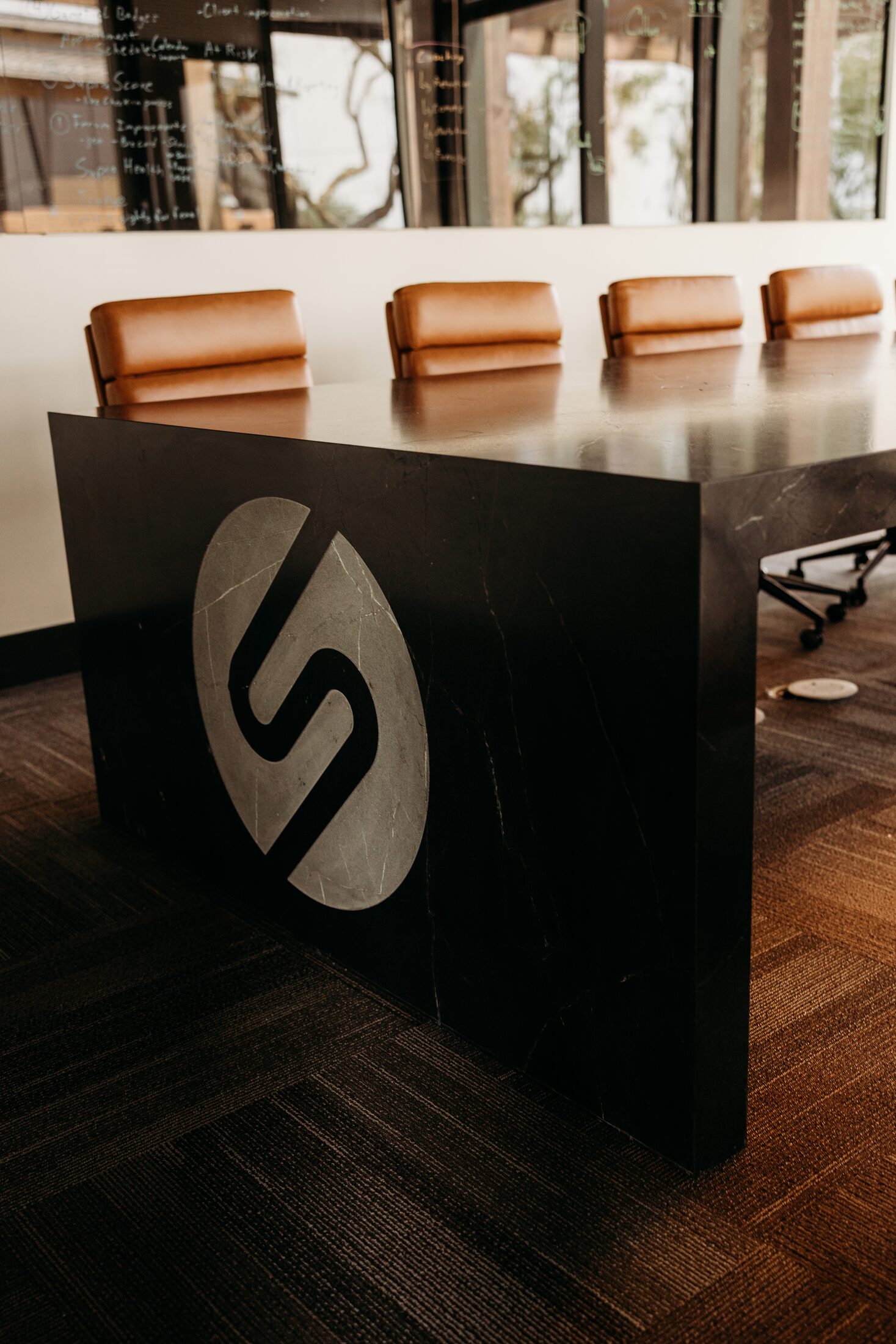 Contrasting stone inlay monogram set into the waterfall end panel of a custom boardroom table