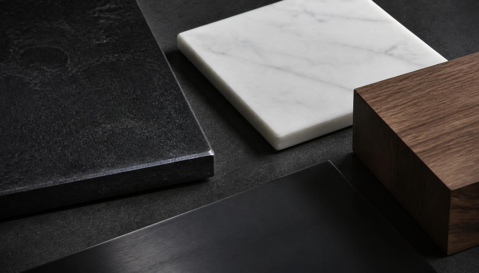 Leathered granite boardroom table top meeting a fluted white oak base, showing the stone and wood materials used in an executive conference table